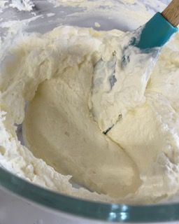 Una ciotola di panna montata con una spatola dentro.