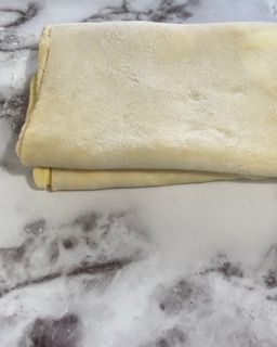 Un pezzo di pasta è appoggiato su un bancone di marmo.