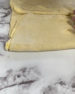 Una persona sta piegando un pezzo di pasta su un tavolo.