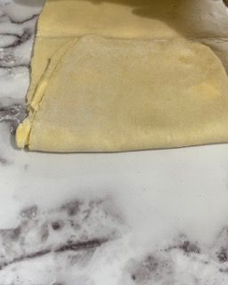 Un pezzo di pasta è appoggiato su un bancone di marmo.