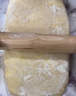 Si usa un mattarello di legno per stendere un pezzo di pasta.