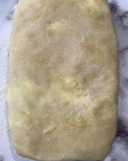 Un pezzo di pasta è appoggiato su un tavolo ricoperto di farina.