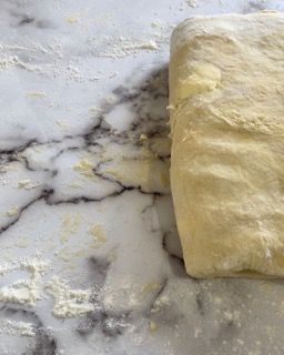 Un pezzo di pasta è appoggiato su un bancone di marmo.