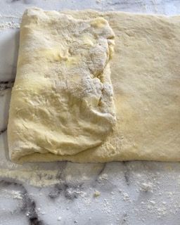 Un pezzo di pasta è appoggiato su un bancone di marmo.