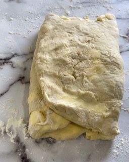 Un pezzo di pasta è appoggiato su un bancone di marmo.