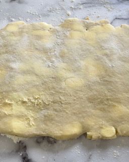 Un pezzo di pasta è appoggiato su un tavolo ricoperto di farina.