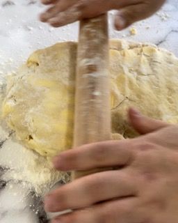 Una persona sta stendendo la pasta con un mattarello.