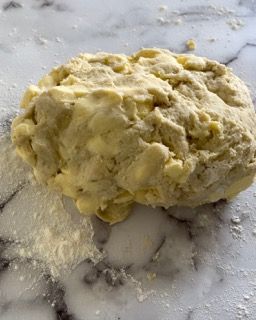 Una palla di pasta è appoggiata su un tavolo ricoperto di farina.