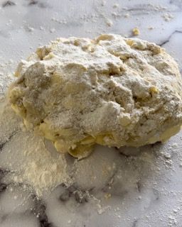 Un pezzo di pasta è appoggiato su un tavolo ricoperto di farina.