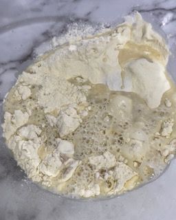 Primo piano di una ciotola di farina e liquido su un tavolo.