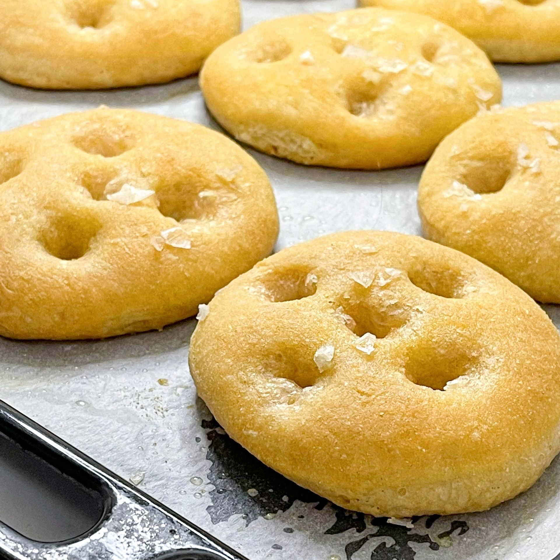 Un mucchio di ciambelle sono adagiate su una teglia da forno.