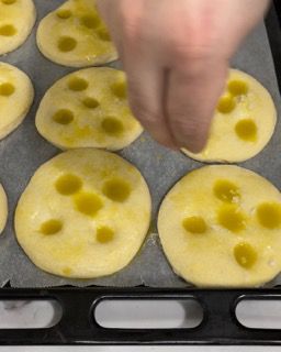 Una persona sta spalmando olio d'oliva su un vassoio di biscotti.
