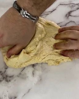Una persona sta impastando l'impasto su un tavolo di marmo.