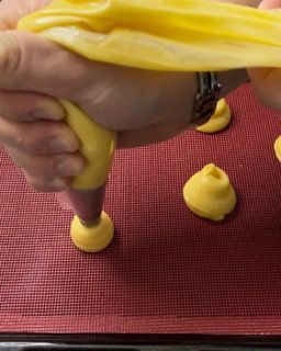 Una persona sta versando la glassa gialla in una tasca da pasticcere.