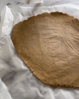 Un pezzo di pasta è appoggiato su un foglio di carta oleata.