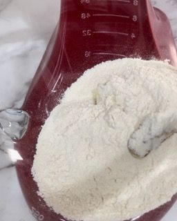 Una tazza graduata con farina e un cucchiaio dentro