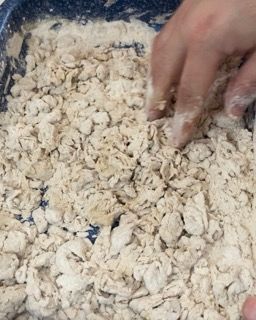 La mano di una persona sta infilando la mano in un mucchio di farina