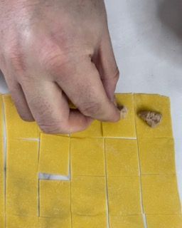 Una persona sta tagliando un pezzo di pasta in quadrati