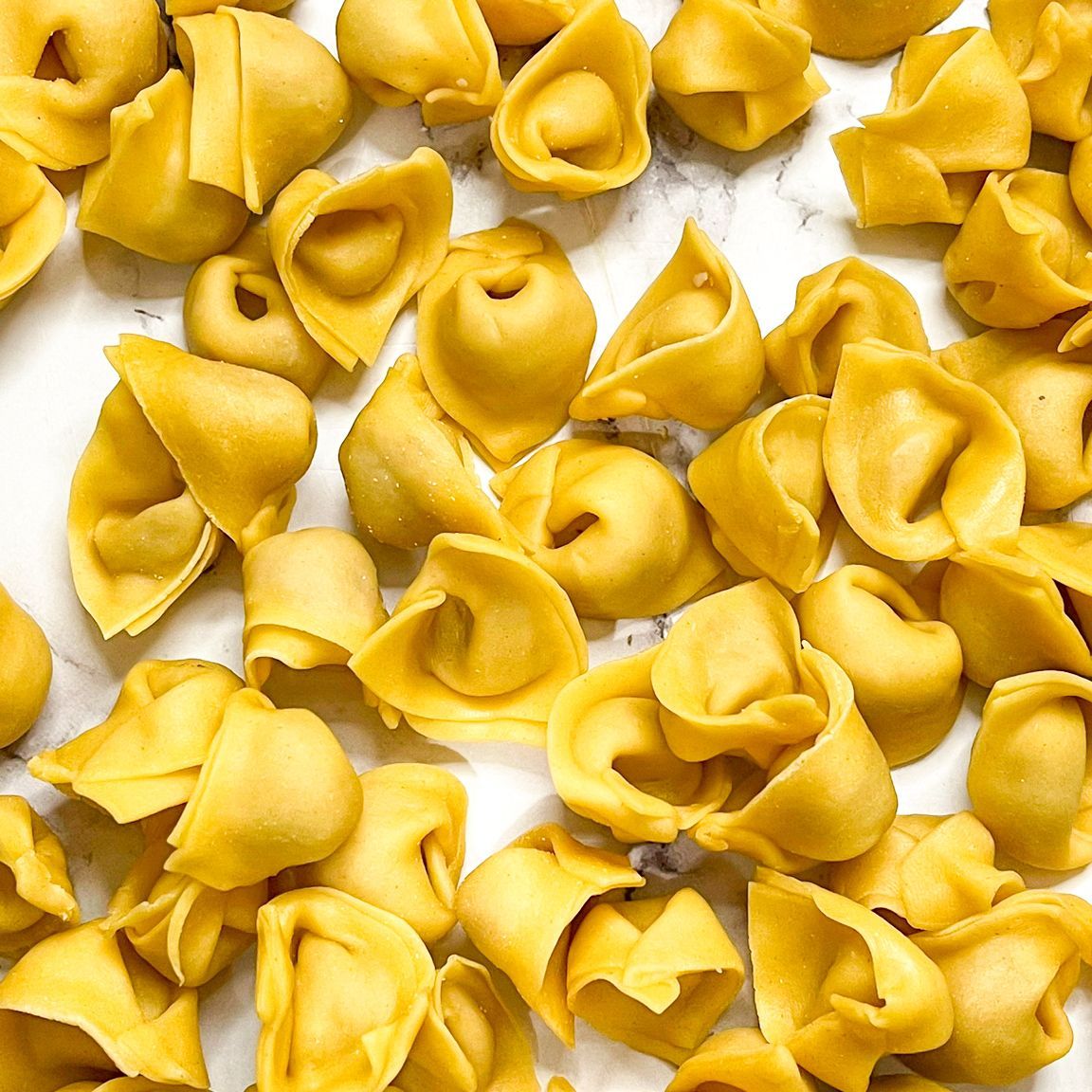 Un mucchio di ravioli gialli su una superficie bianca