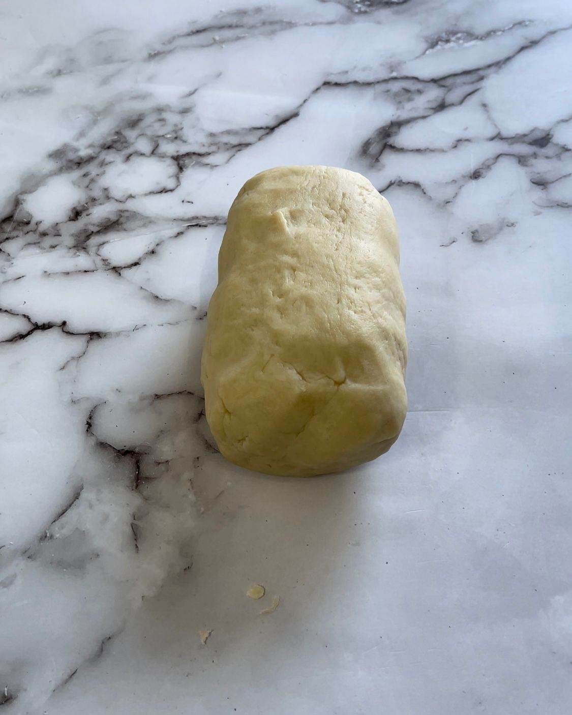 Un pezzo di pasta è appoggiato su una superficie di marmo.