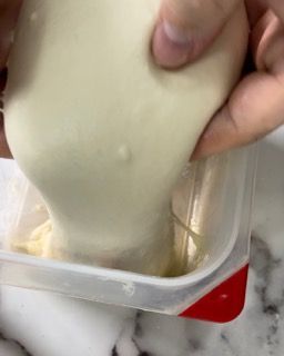 Una persona sta versando un liquido bianco in un contenitore di plastica.