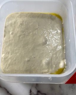 Un contenitore di plastica pieno di un liquido bianco è appoggiato su un tavolo.