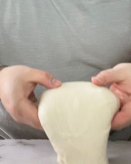 Una persona tiene in mano una palla di melma bianca.