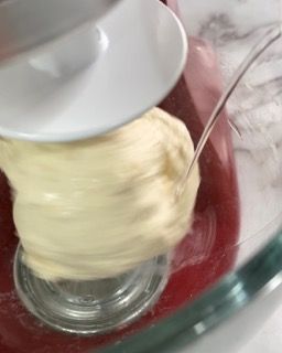 Una persona sta mescolando qualcosa in una ciotola di vetro con un mixer.