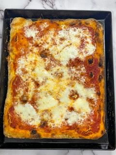 Una pizza è appoggiata su una teglia su un tavolo.