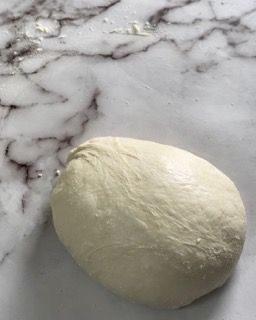Una palla di pasta è appoggiata su una superficie di marmo.