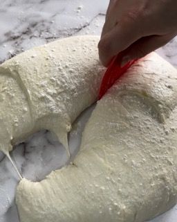 Una persona tiene una spatola sopra un pezzo di impasto.