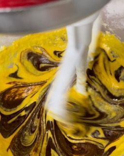 Primo piano di un mixer che mescola un liquido giallo e uno marrone.