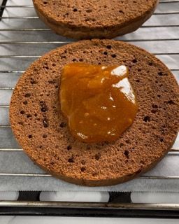 Un pezzo di torta con sopra una salsa è appoggiato su una griglia di raffreddamento.