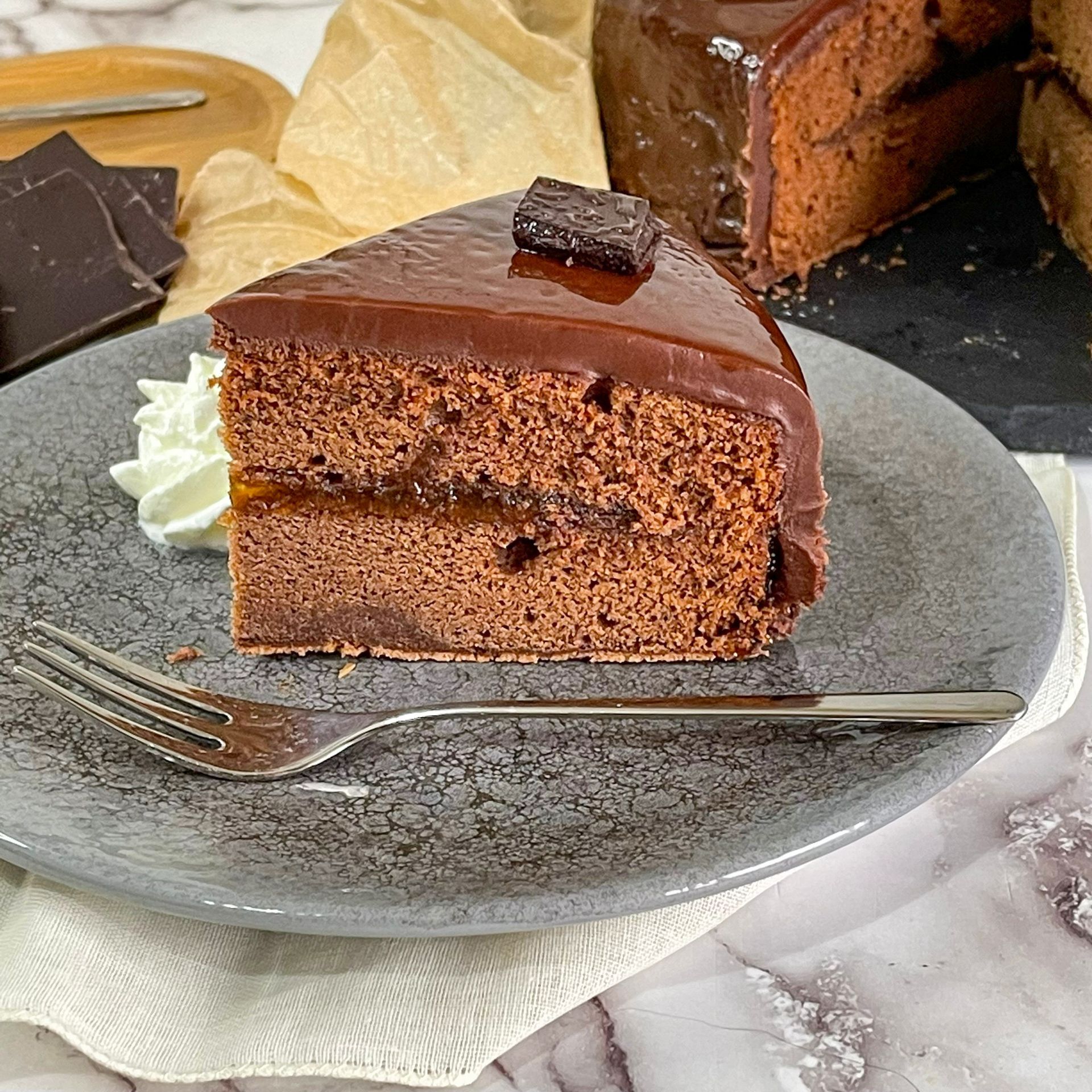 Una fetta di torta al cioccolato su un piatto con panna montata e una forchetta.