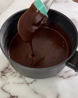 Una persona sta versando la salsa al cioccolato in una pentola con una spatola.