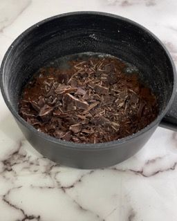 Una pentola piena di gocce di cioccolato e acqua su un tavolo.