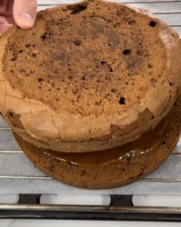 Una persona tiene in mano un pezzo di torta su una griglia di raffreddamento.