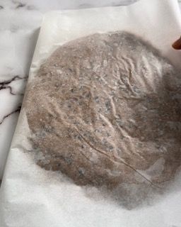 Un pezzo di pasta è appoggiato su un foglio di carta oleata.