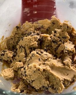 Una ciotola di pasta per biscotti con un misurino sullo sfondo