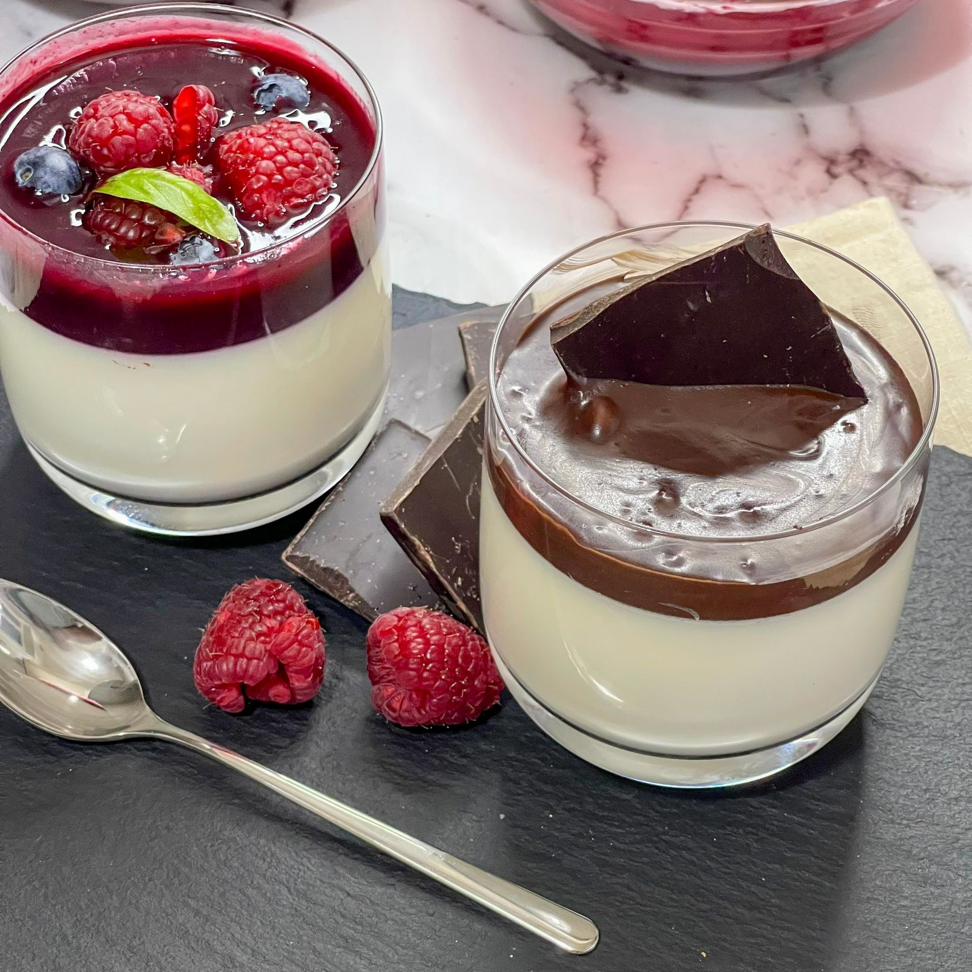 Due bicchieri di dessert con lamponi e cioccolato sopra