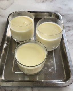 Tre bicchieri di latte sono su un vassoio su un tavolo.