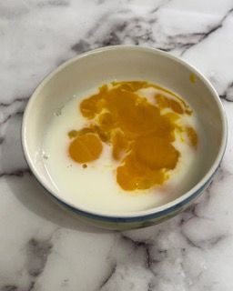 Una ciotola di latte e miele su un tavolo di marmo.