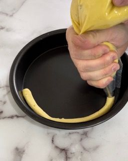 Una persona sta versando un liquido giallo in una padella.