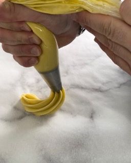 Una persona sta versando la glassa gialla in una tasca da pasticcere.
