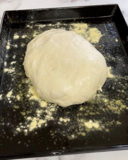 Una palla di pasta è appoggiata su un vassoio ricoperto di farina