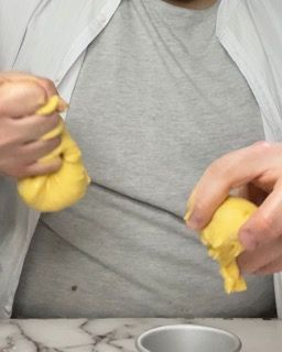 Una persona tiene in mano un pezzo di pasta gialla.