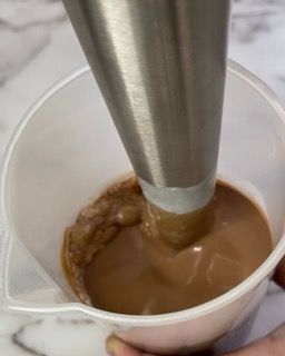 Una persona sta versando del cioccolato in un misurino.