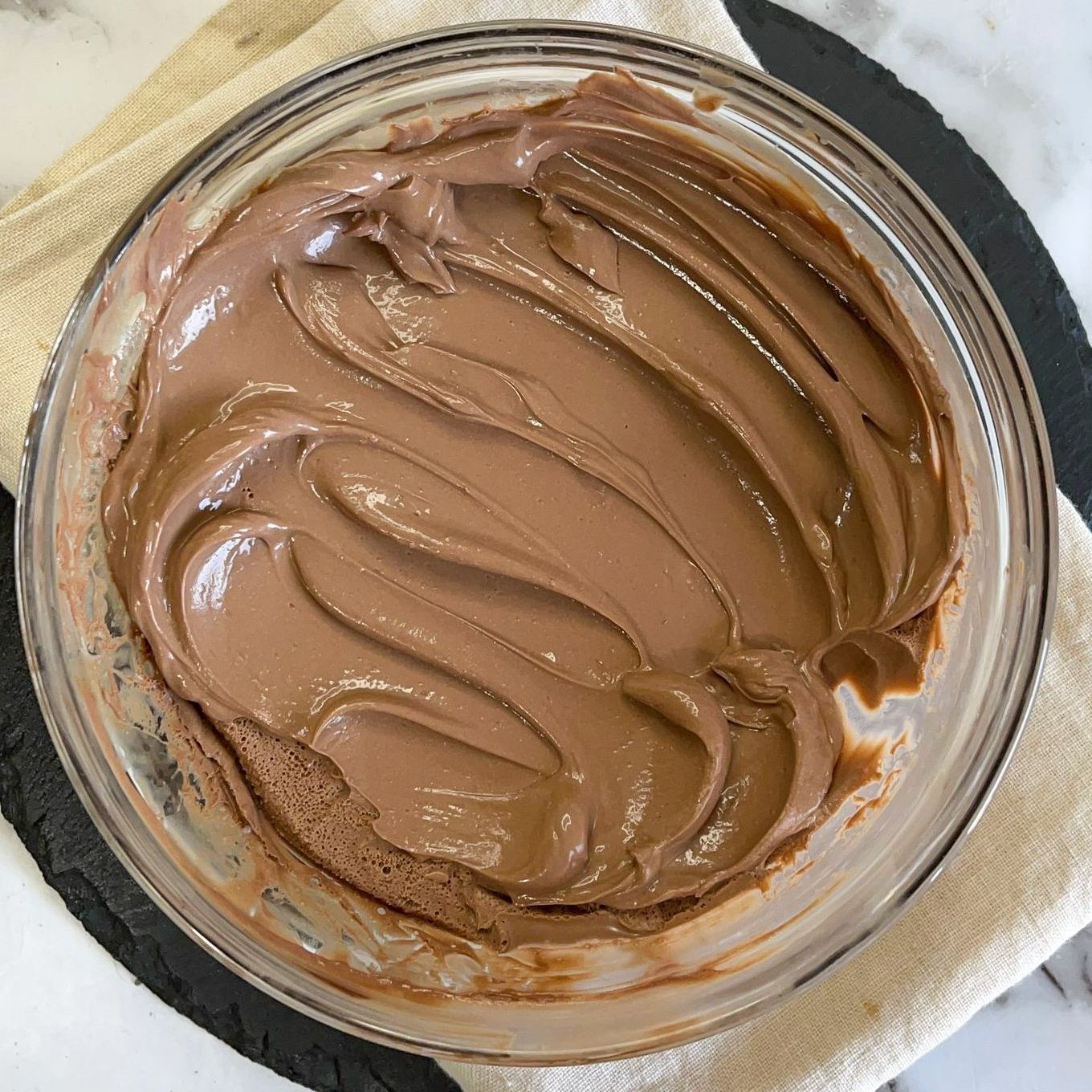 Una ciotola di glassa al cioccolato è appoggiata su un tavolo.