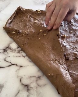Una persona sta facendo rotolare un pezzo di cioccolato su una superficie di marmo