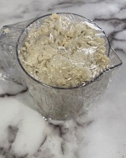 Un misurino pieno di impasto è avvolto nella pellicola trasparente.